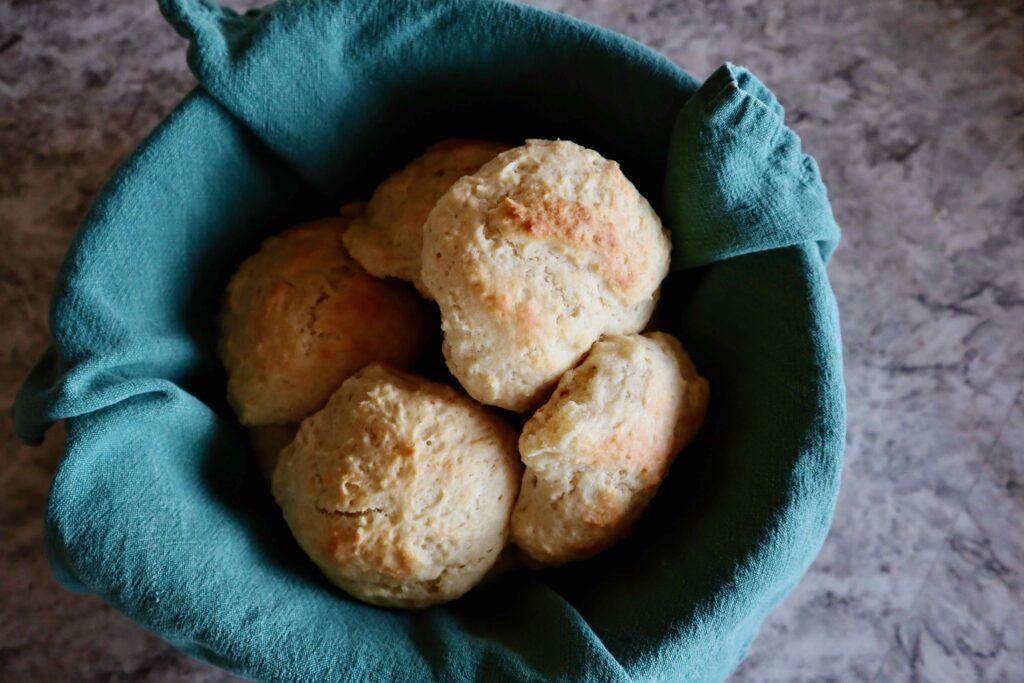 Sourdough drop biscuits in a blue napkin lined basket.