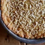 Almond Ring shortbread cake covered with slivered almonds in a round pan.