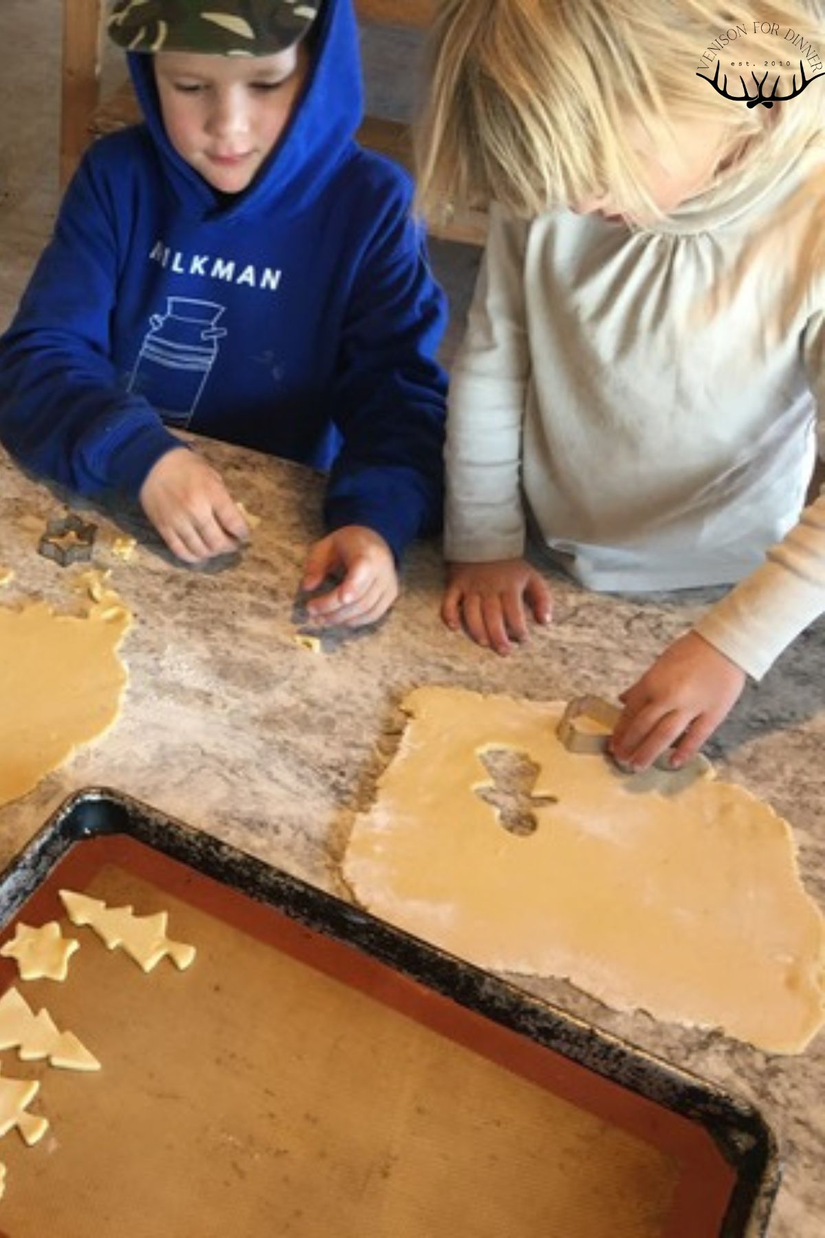 Two kids using cookie cutters on dough.