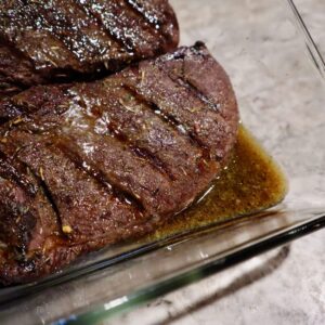 Grilled venison steaks in a glass baking dish.