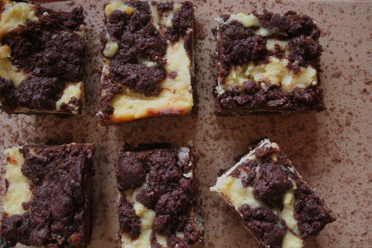 Cheesecake brownie squares on a wood board.