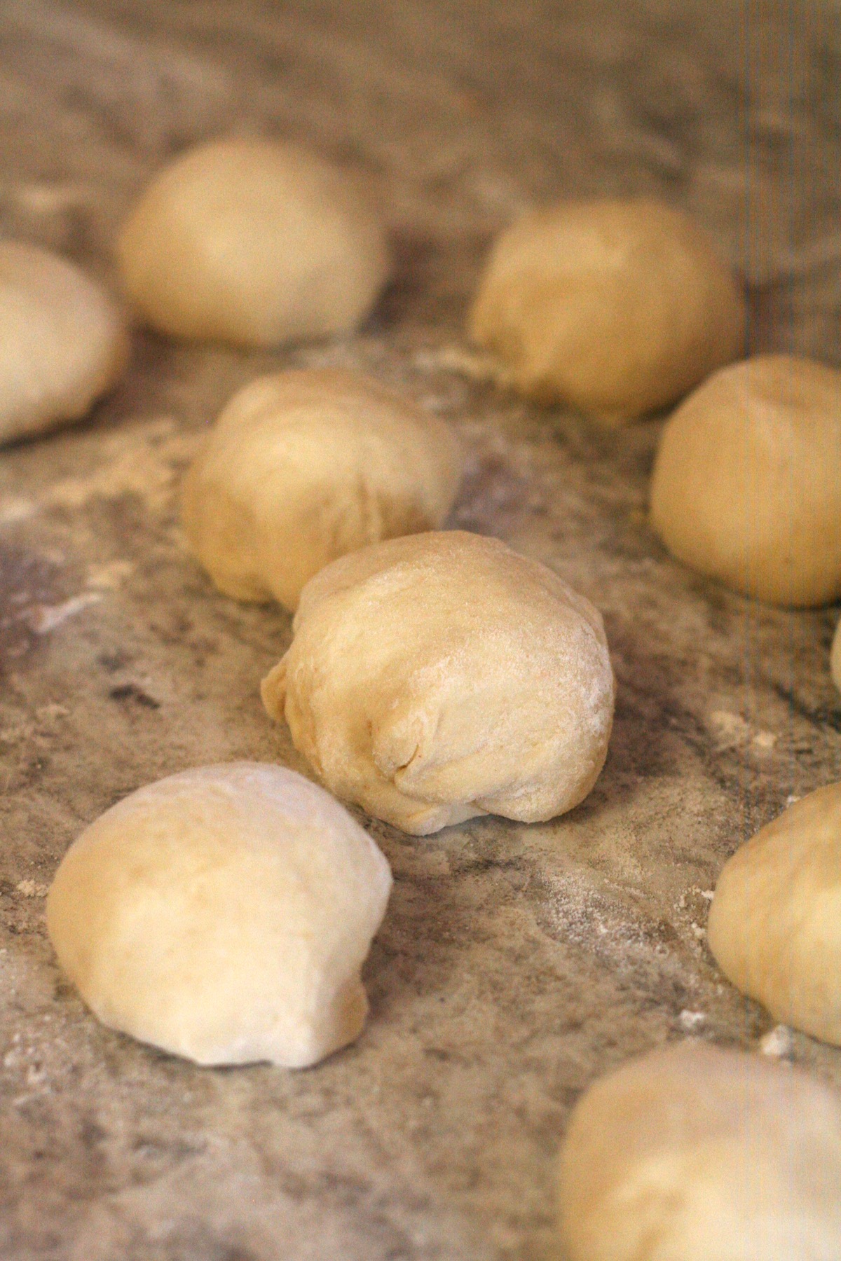 Formed dinner rolls on a floured counter.