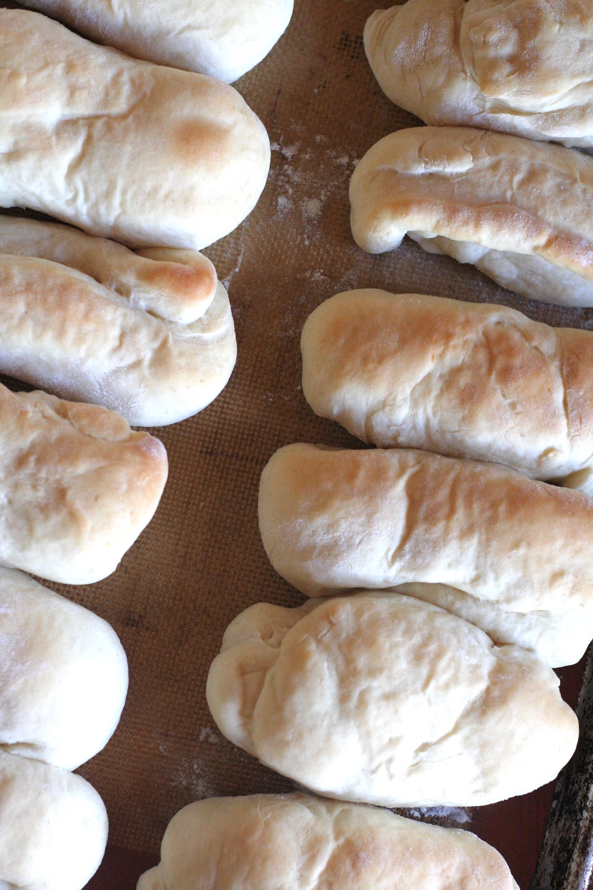 Baked hot dog buns on a silicone mat.