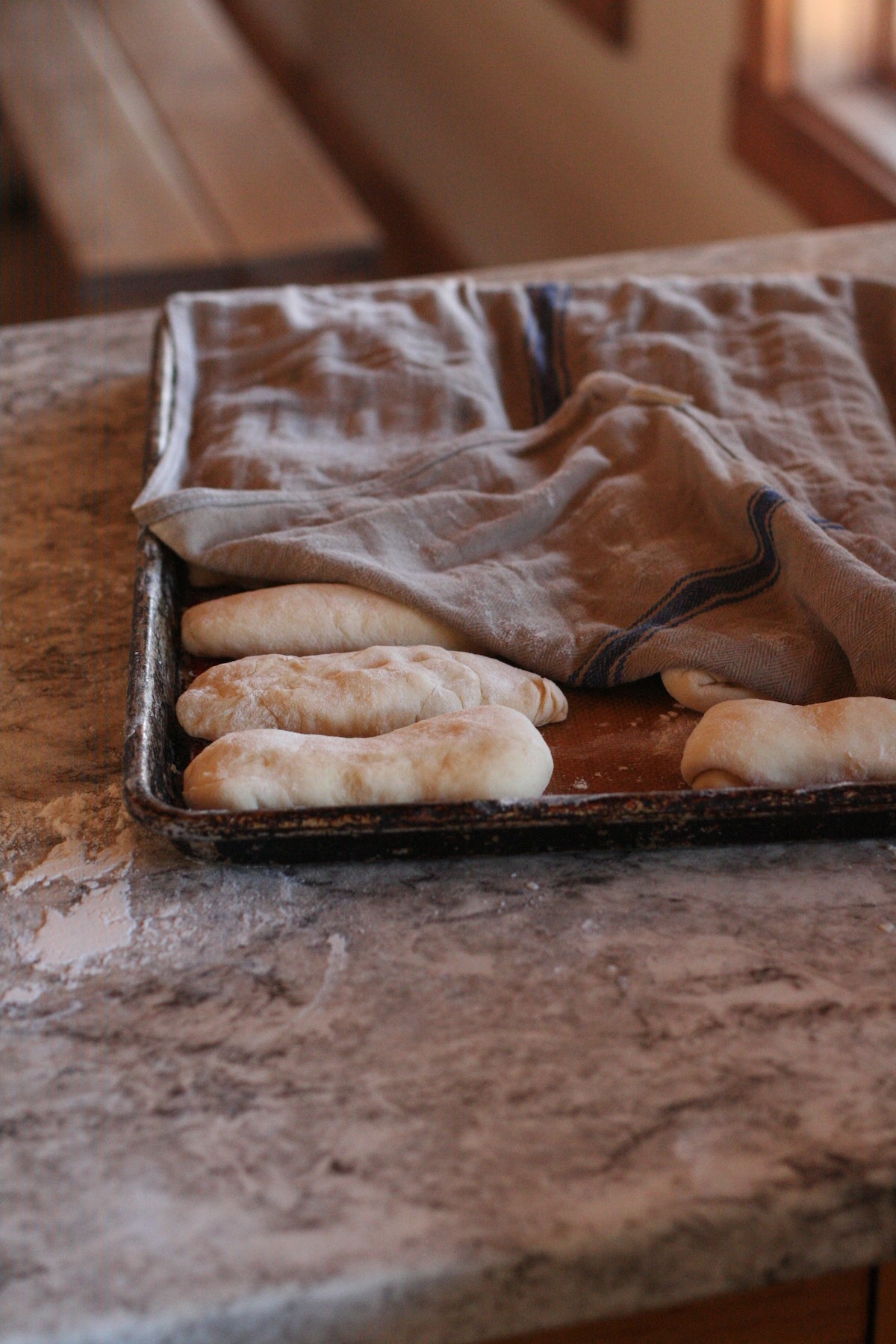 Hot dog buns proofing under a towel.