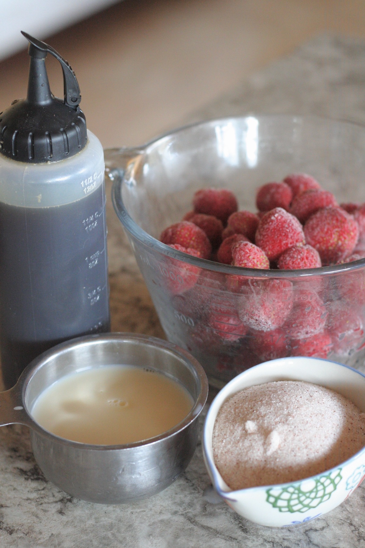 Ingredients to make strawberry soft serve in bowls on a counter.