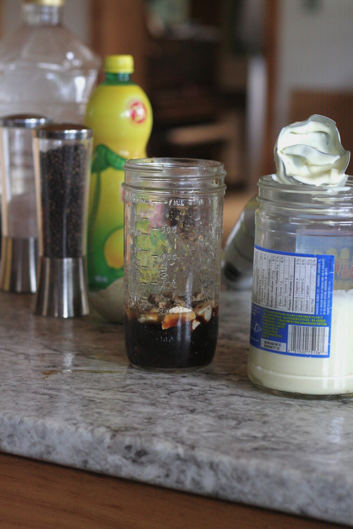 Garlic infused oil in a jar next to a jar of Caesar dressing.