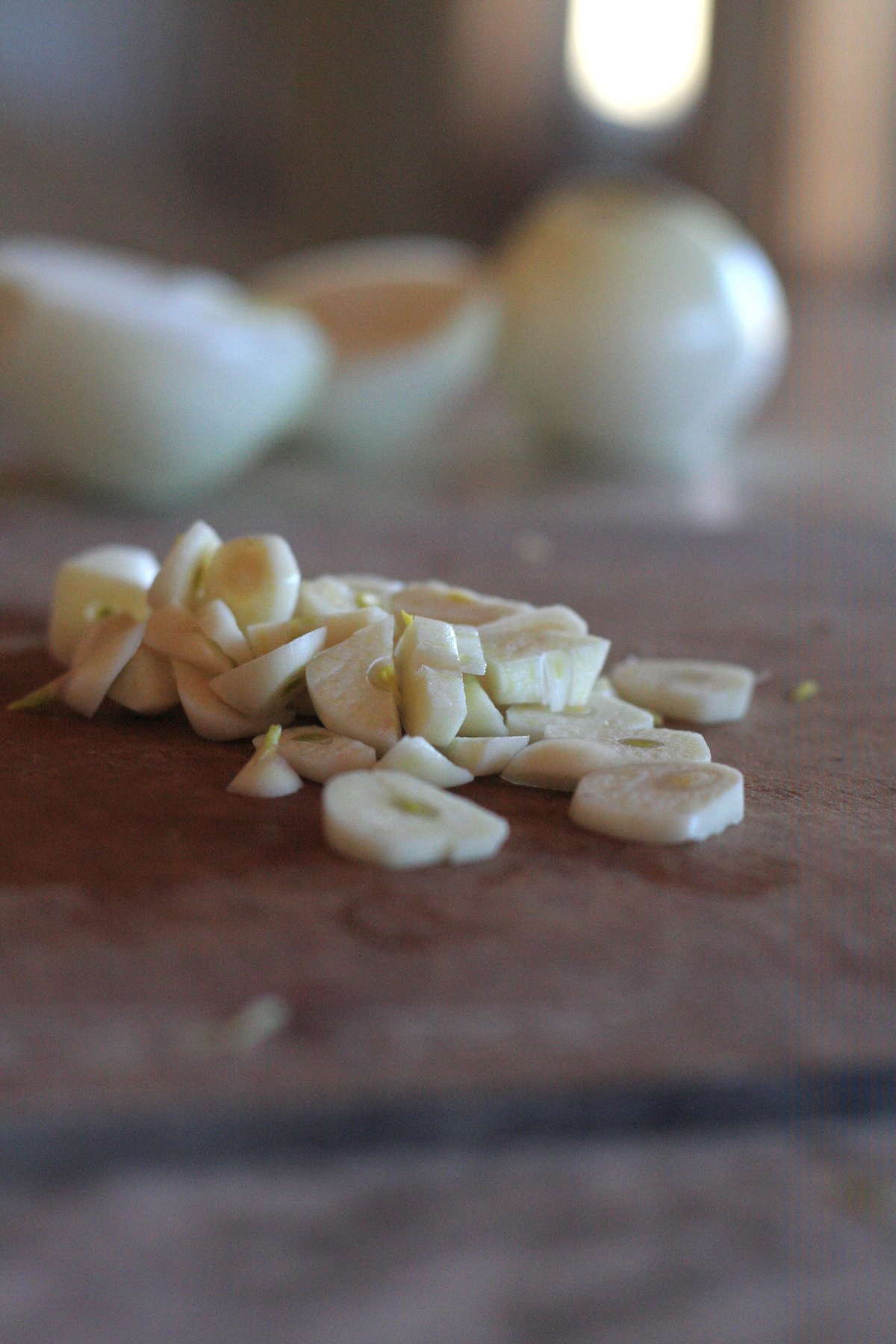 Sliced garlic on a wooden cutting board.