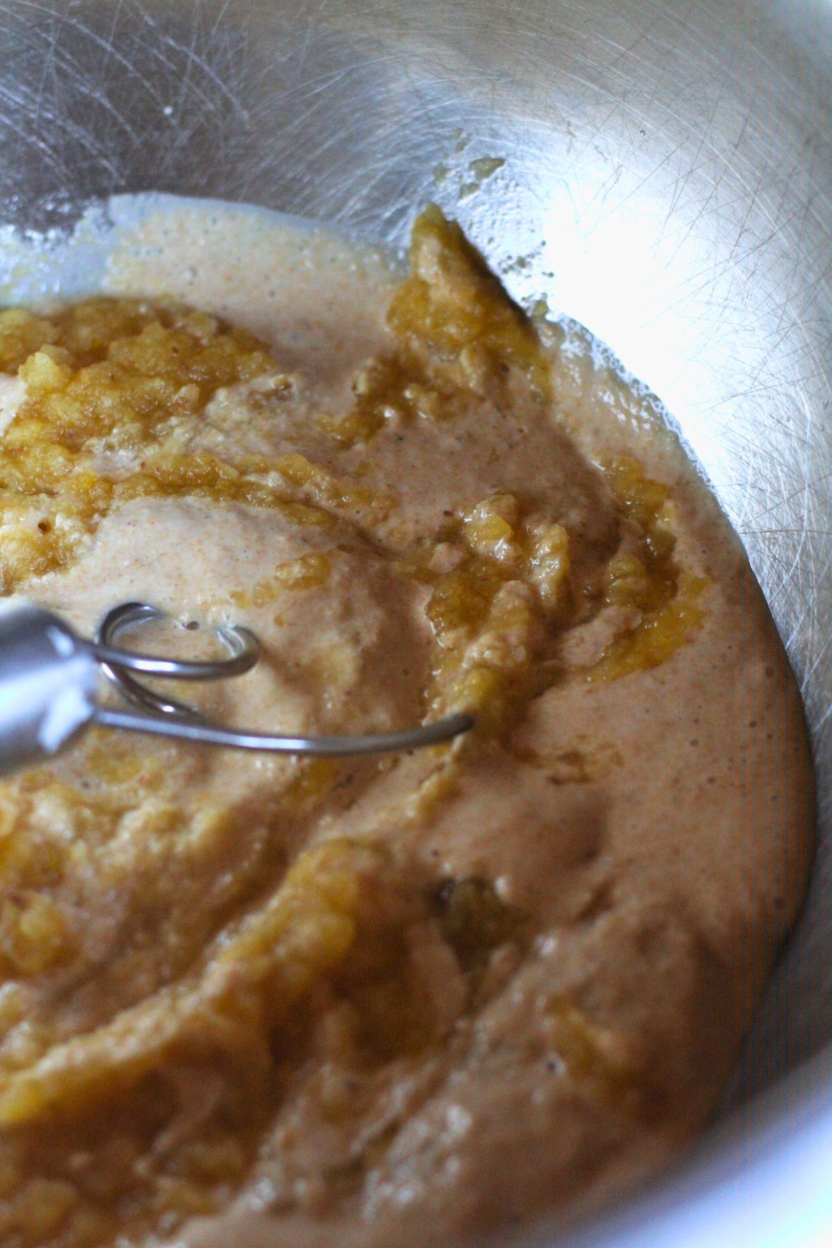 A Danish dough whisk in a bowl of pumpkin muffin batter.