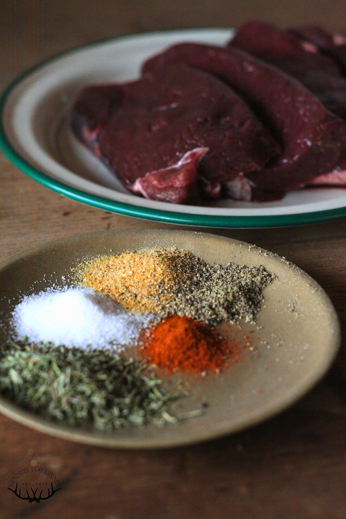 A plate of seasoning in front of a stack of moose steaks.