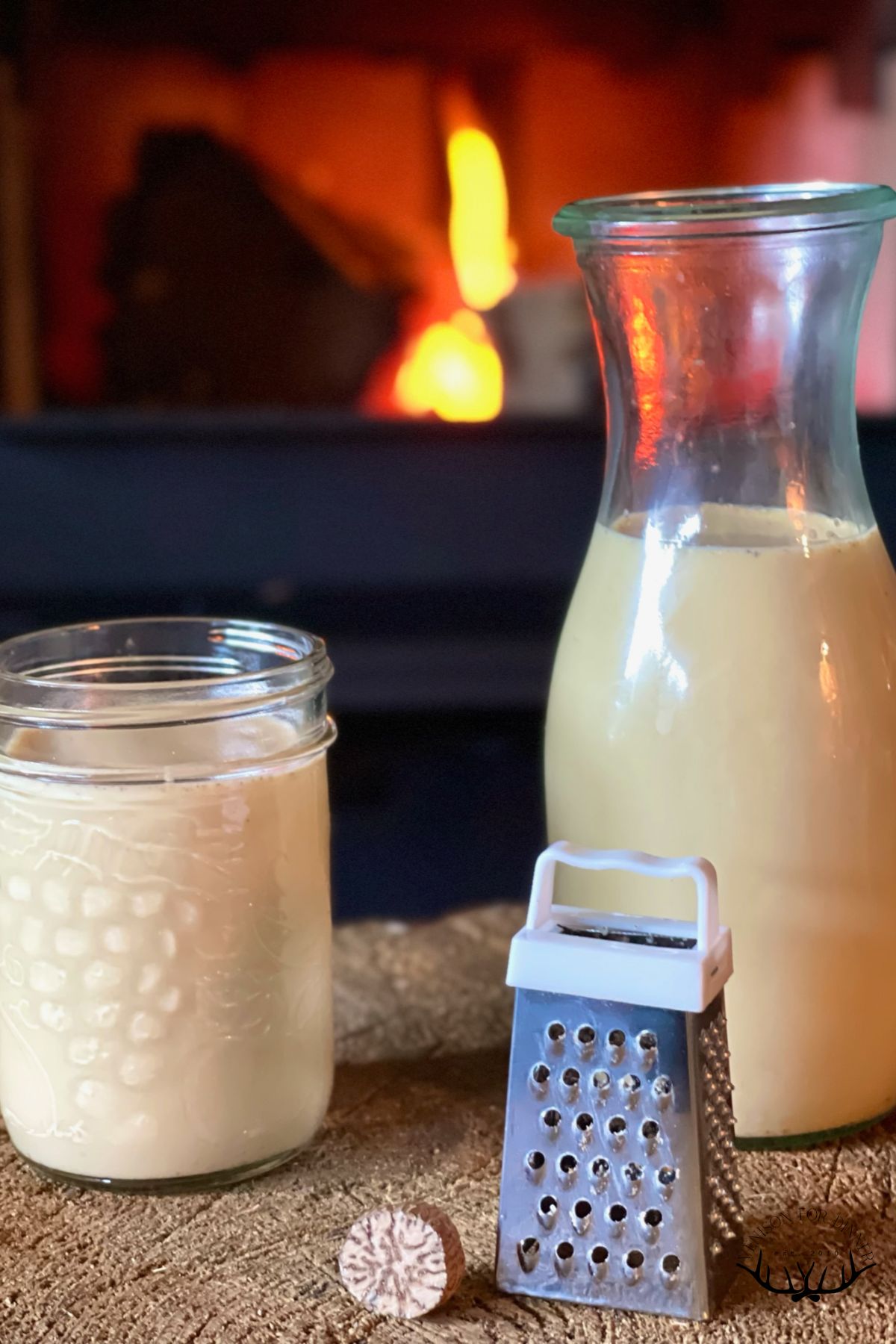 Raw egg nog in two jars next to a mini grater and whole nutmeg.