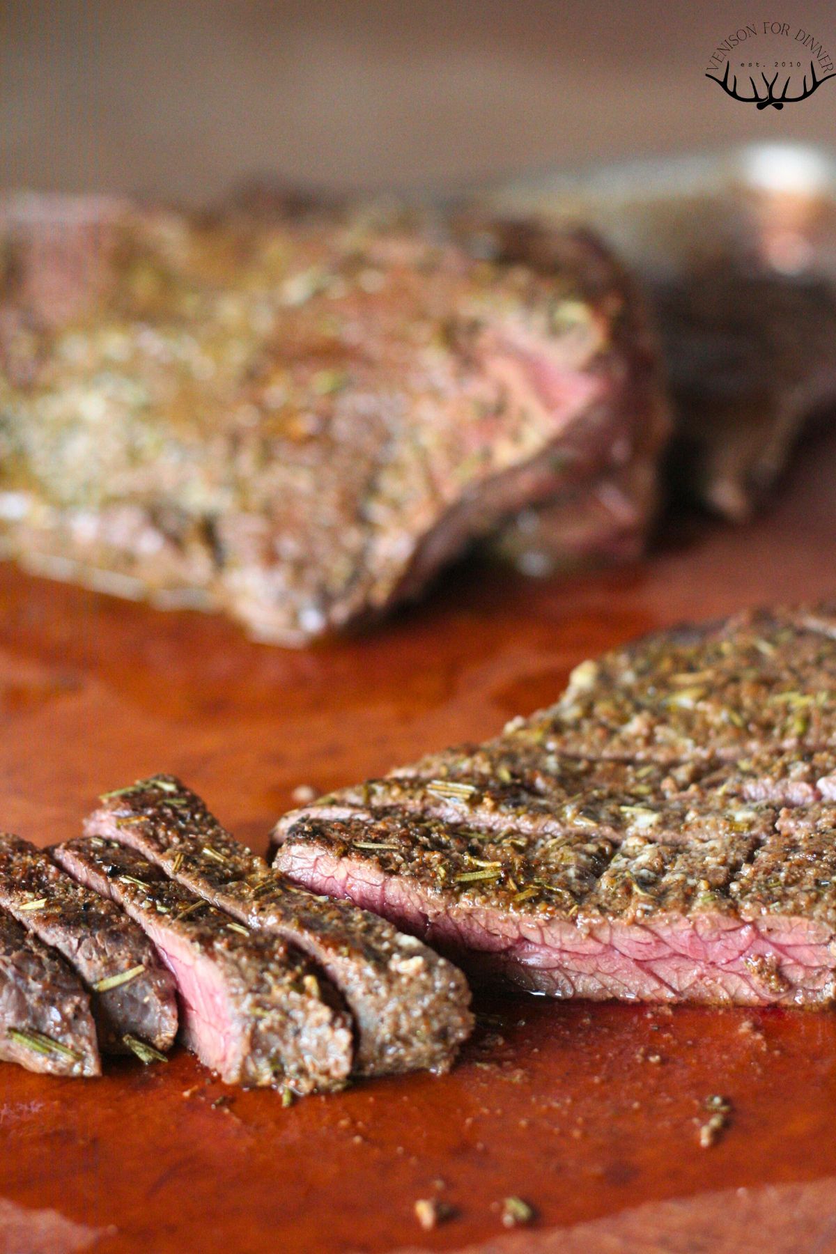 Sliced moose steak on a wooden cutting board.