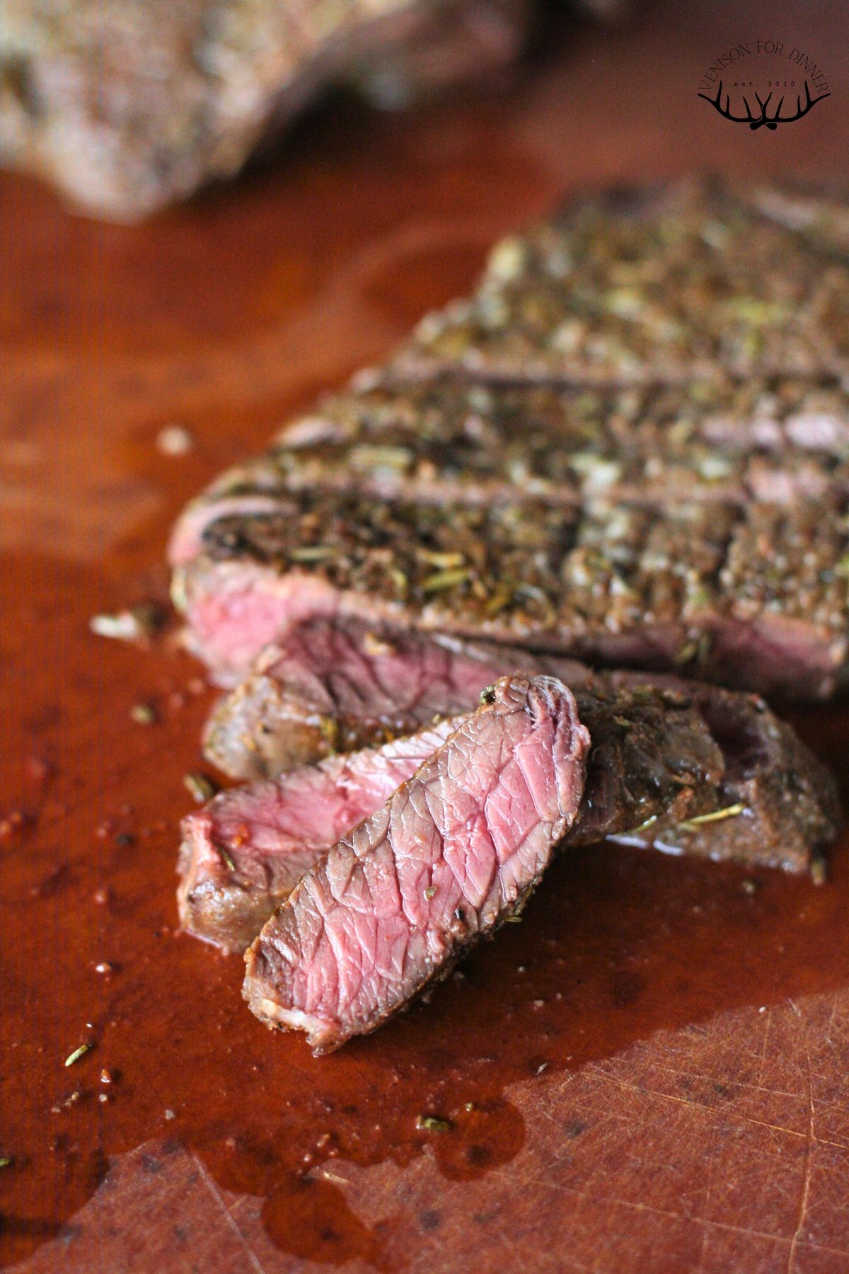 Sliced moose steak on a wooden cutting board.