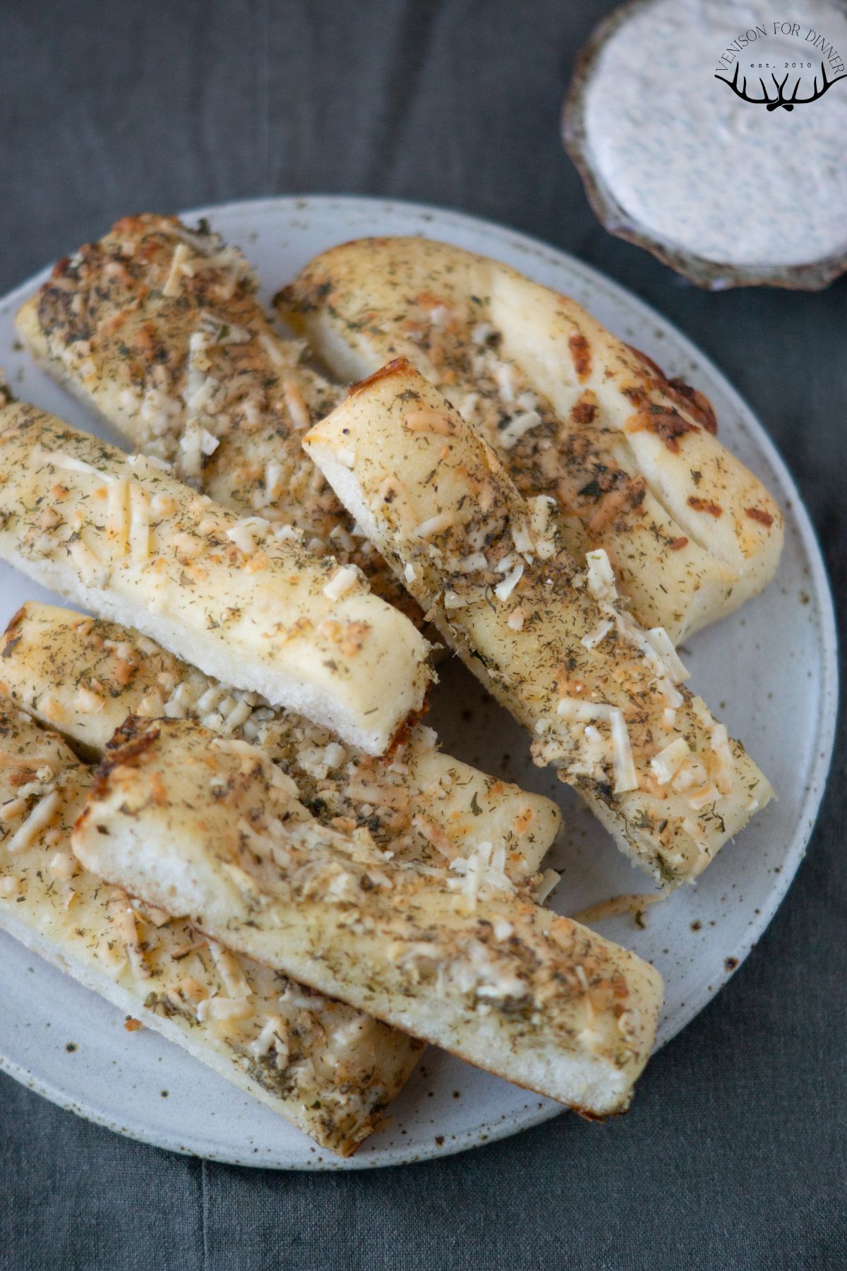 Pile of ranch bread sticks on a white plate.