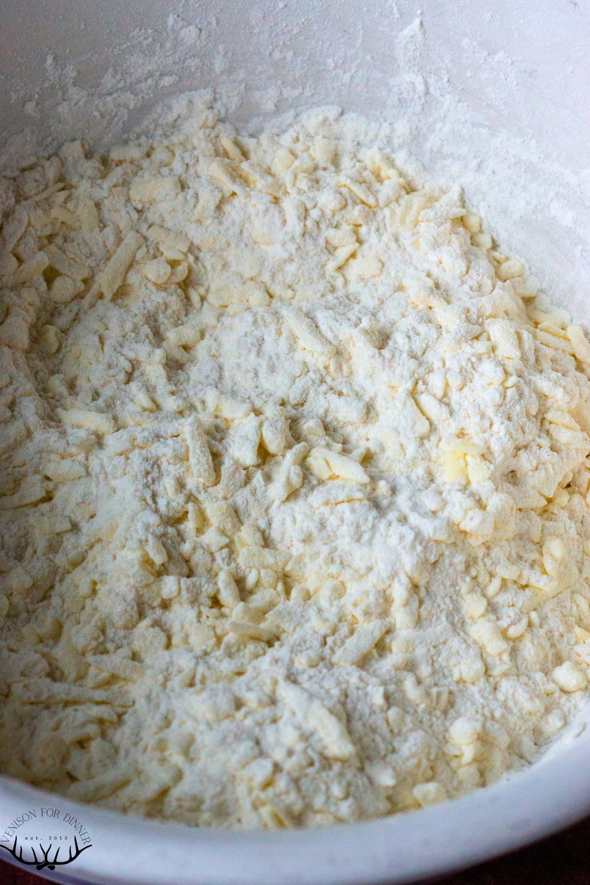 Grated butter coated in flour in a mixing bowl.