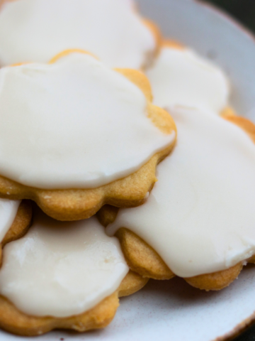 Pile of iced cut out cookies on a plate.