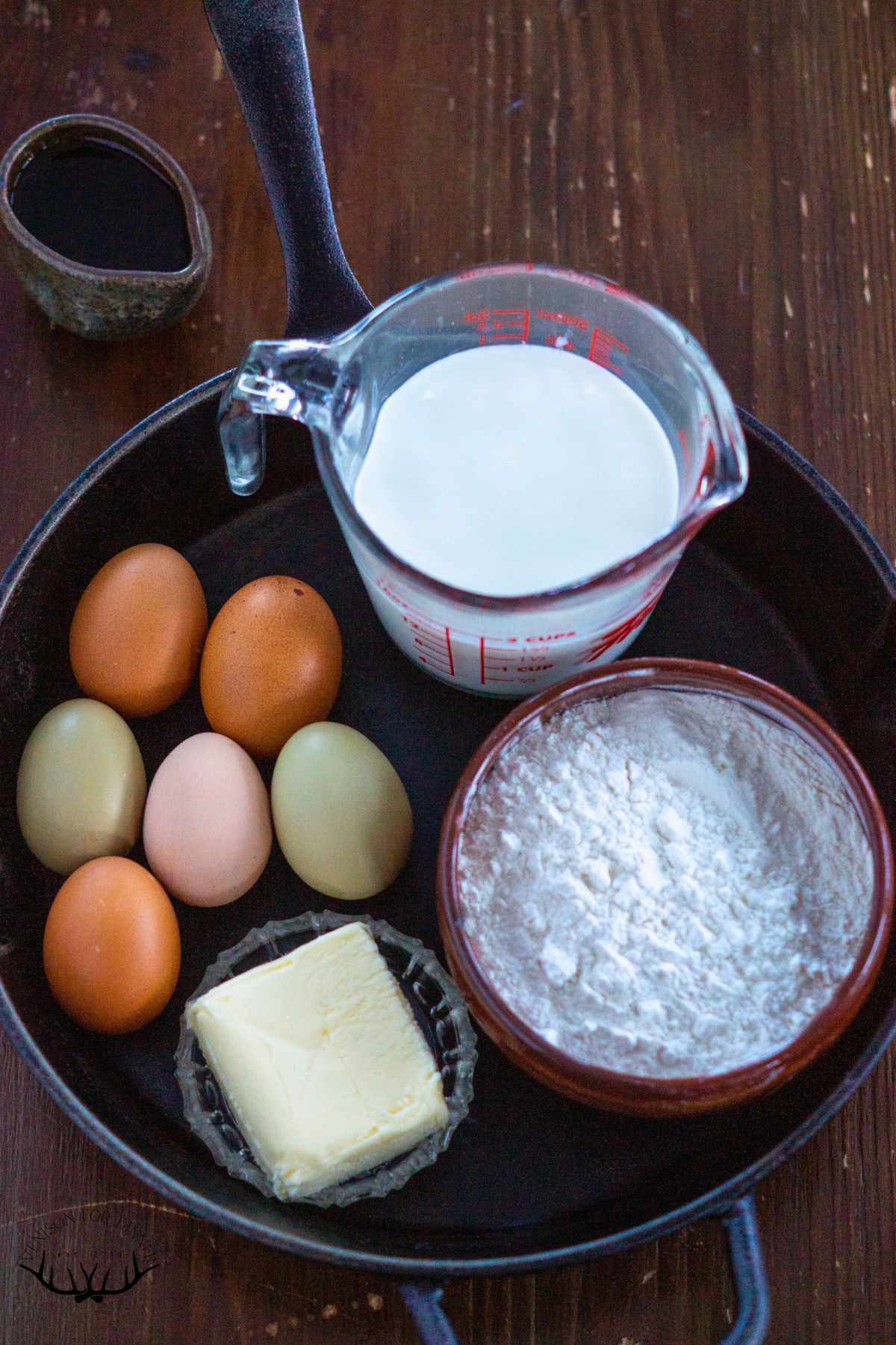 Ingredients to make Dutch baby pancake set in a cast iron skillet.