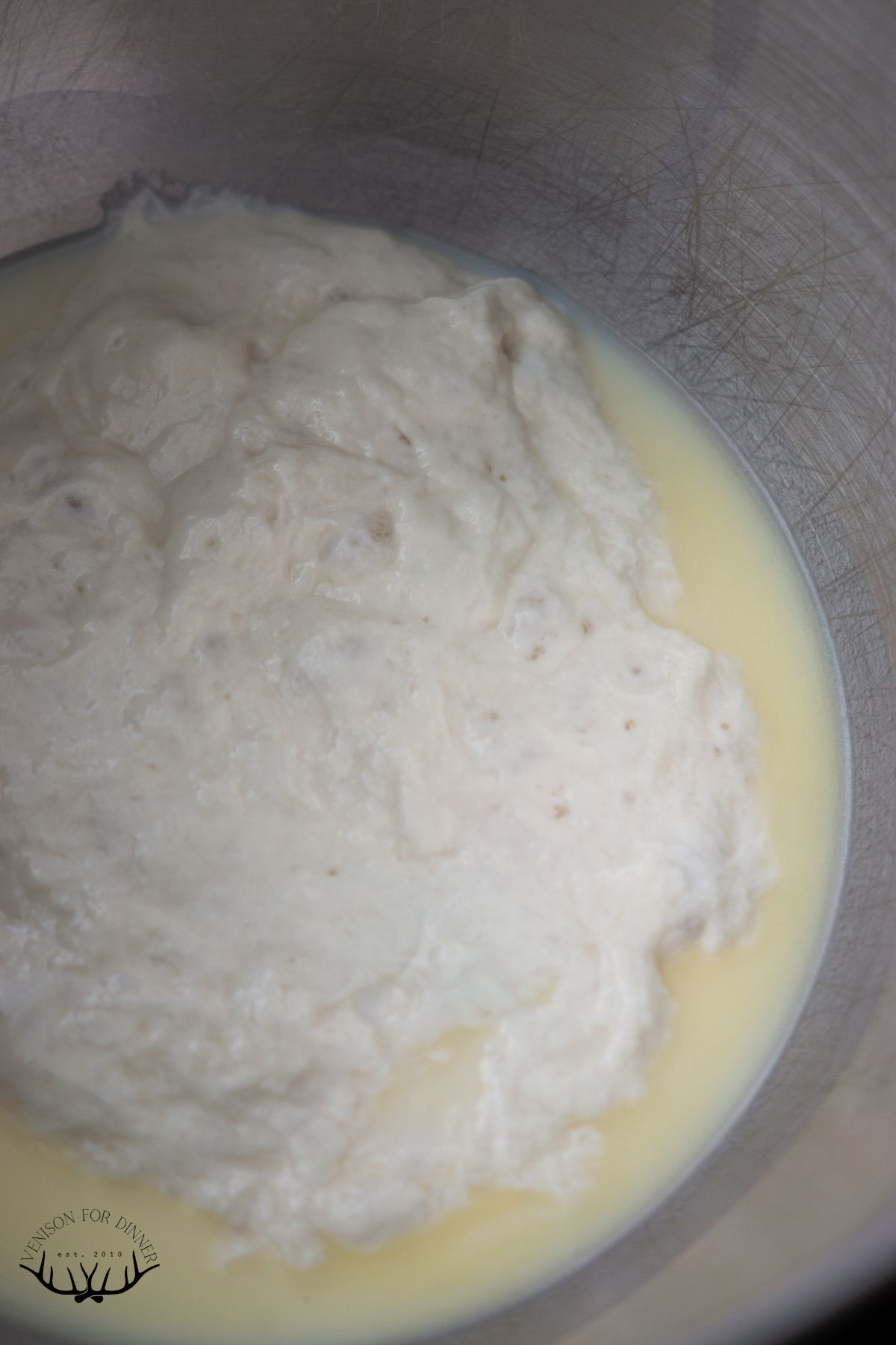 Sourdough starter, butter, and milk in the bowl of a stand mixer.