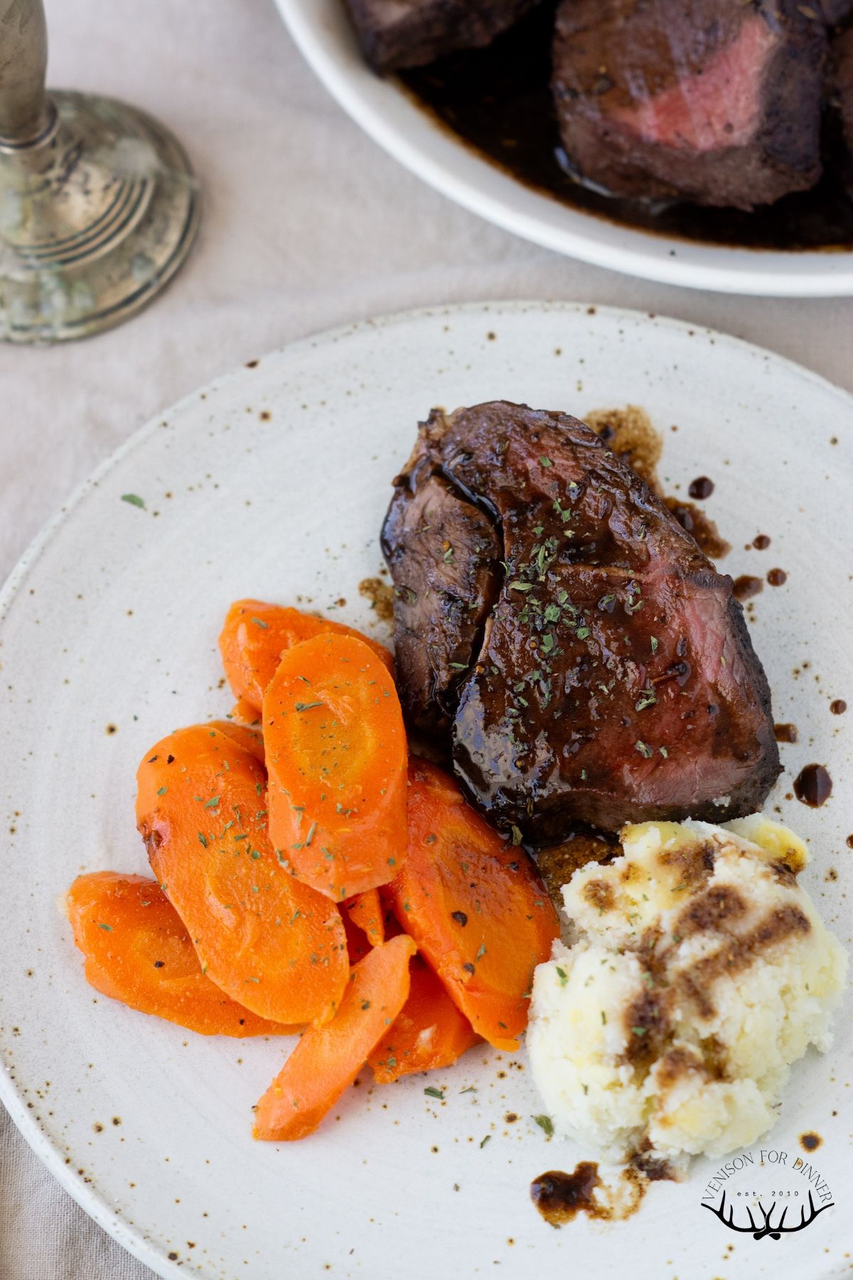 Venison with carrots and potatoes on a plate.