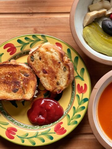 A grilled cheese sandwich next to soup.