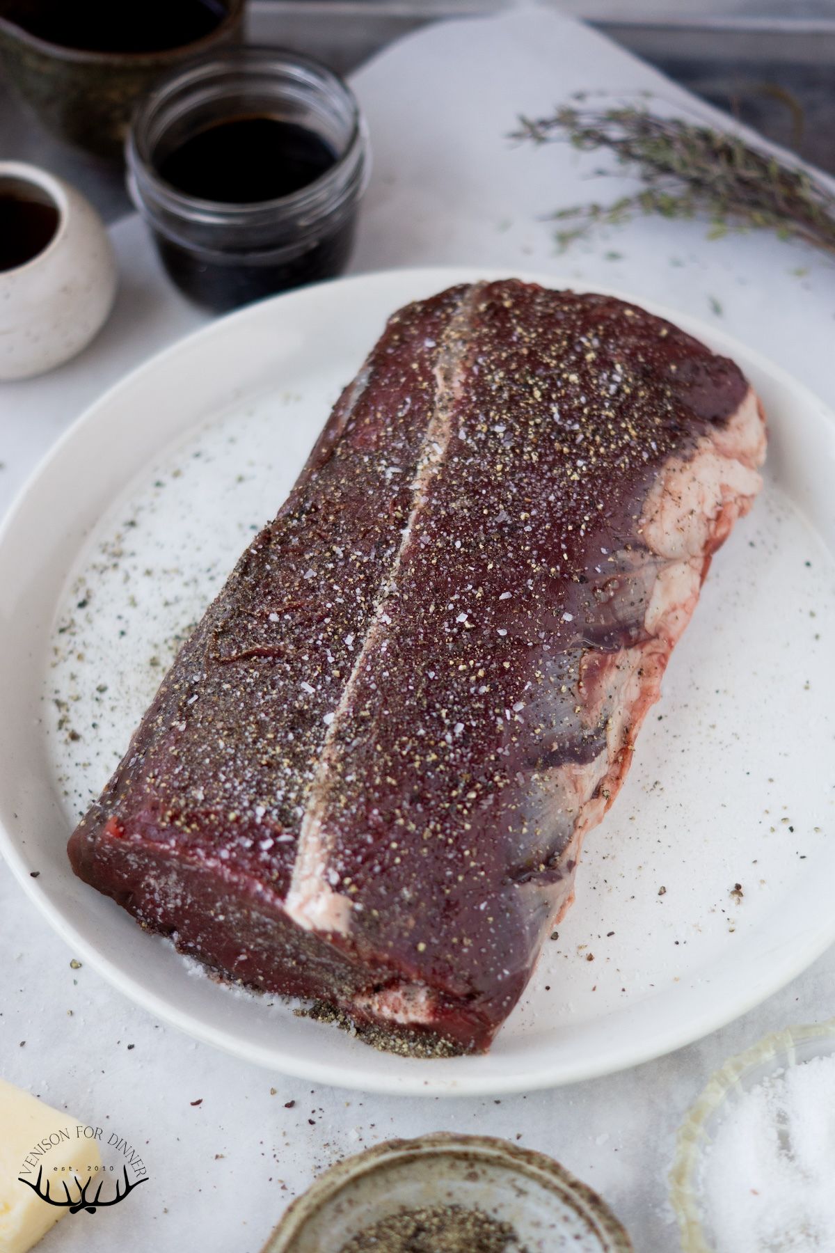 Venison backstrap rubbed with seasoning on a plate.