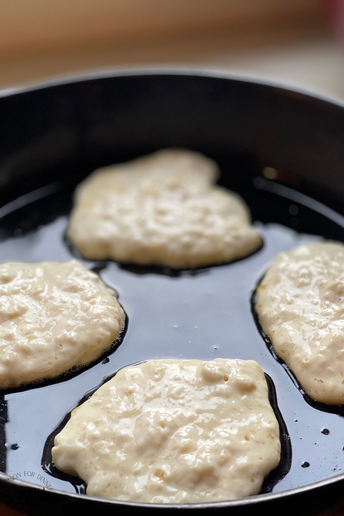 Pancakes frying in an oiled skillet.