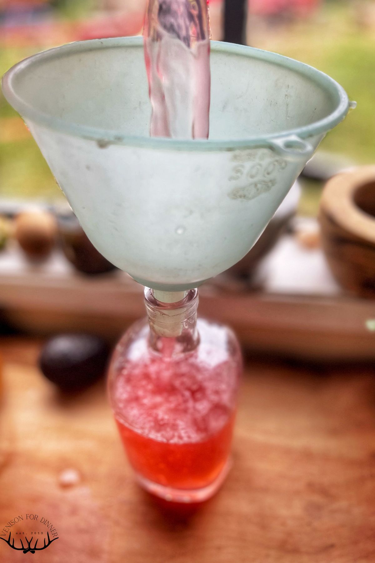 Funneling raspberry soda into bottles.