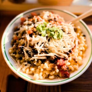 Bowl of chili macaroni and cheese with all the toppings.