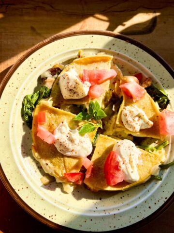 Spinach mushroom quesadilla topped with sour cream and tomatoes.
