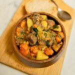 Venison, carrot, and potato stew in a wooden bowl.