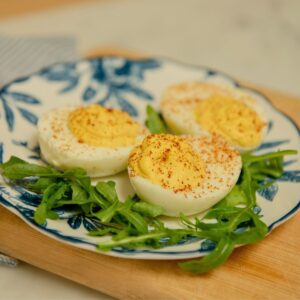 A plate of three deviled egg halves with paprika.
