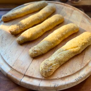 Baked garlic breadsticks on a wooden board.