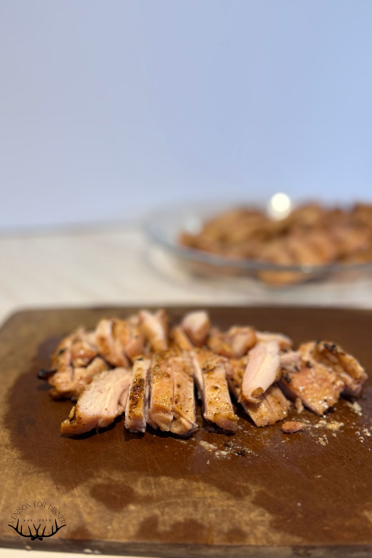 Sliced up chicken thighs on a wooden cutting board.