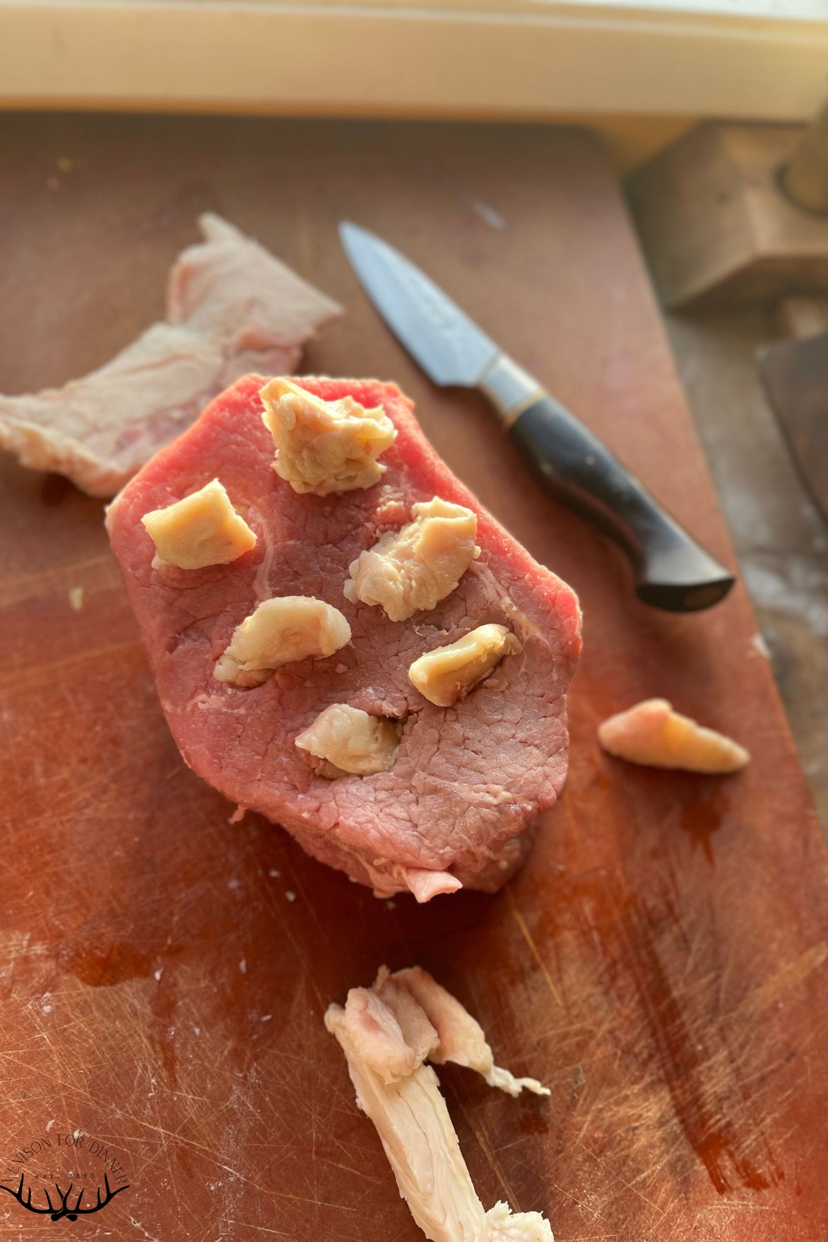Slices of fat tucked into a deer roast.