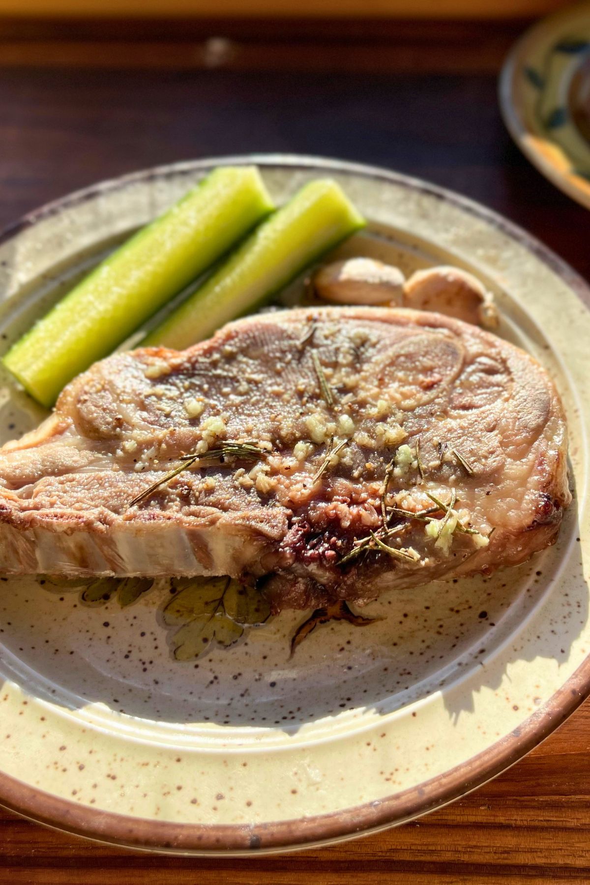 Finished roasted lamb chop on a plate with zucchini.