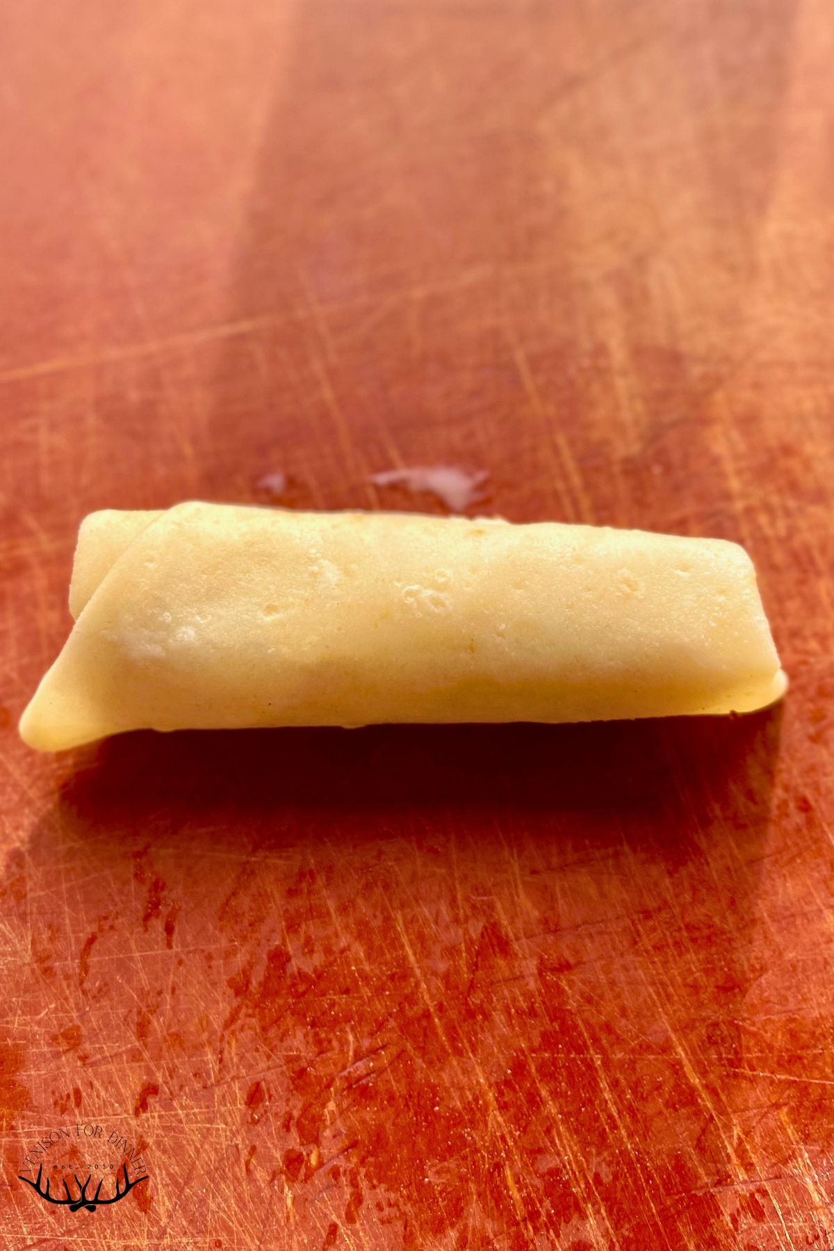 Spring roll wrapped up, on a cutting board.