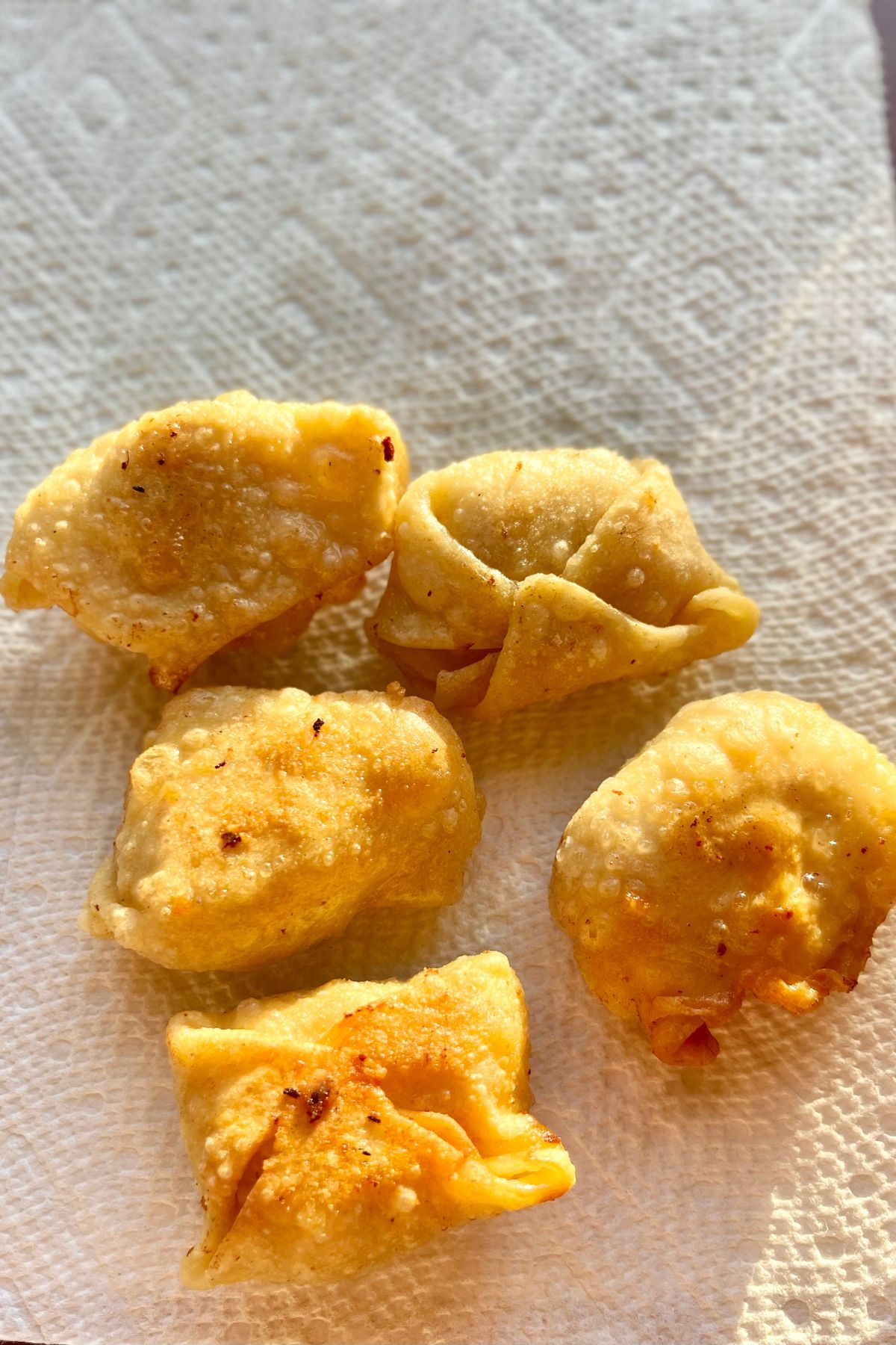 Fried won tons draining on paper towel.