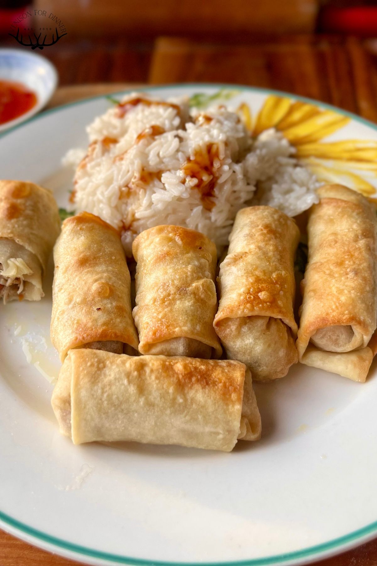 Spring rolls and white rice on a plate.