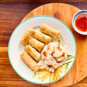 Pork spring rolls with white rice on a plate.