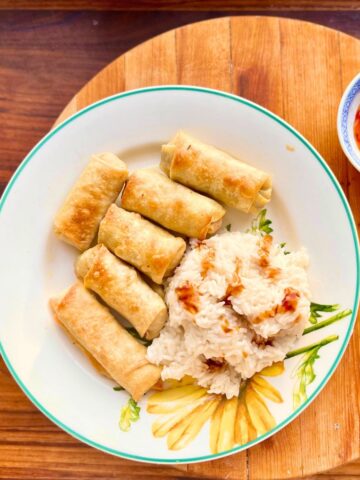 Pork spring rolls with white rice on a plate.