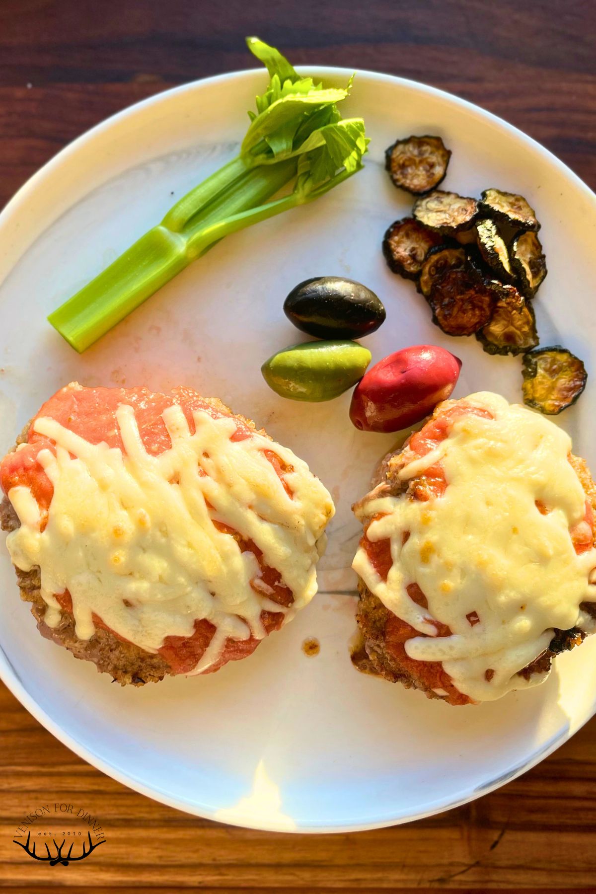 Two venison parmesan cutlets on a plate.