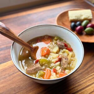 Spoon in a bowl of venison soup with barley.