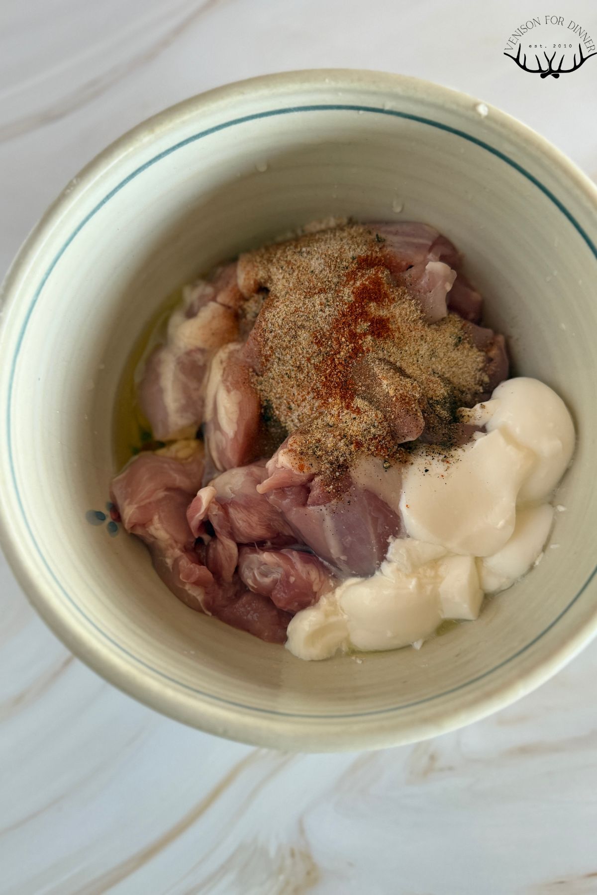 Seasoned yogurt and chicken thighs in a mixing bowl.