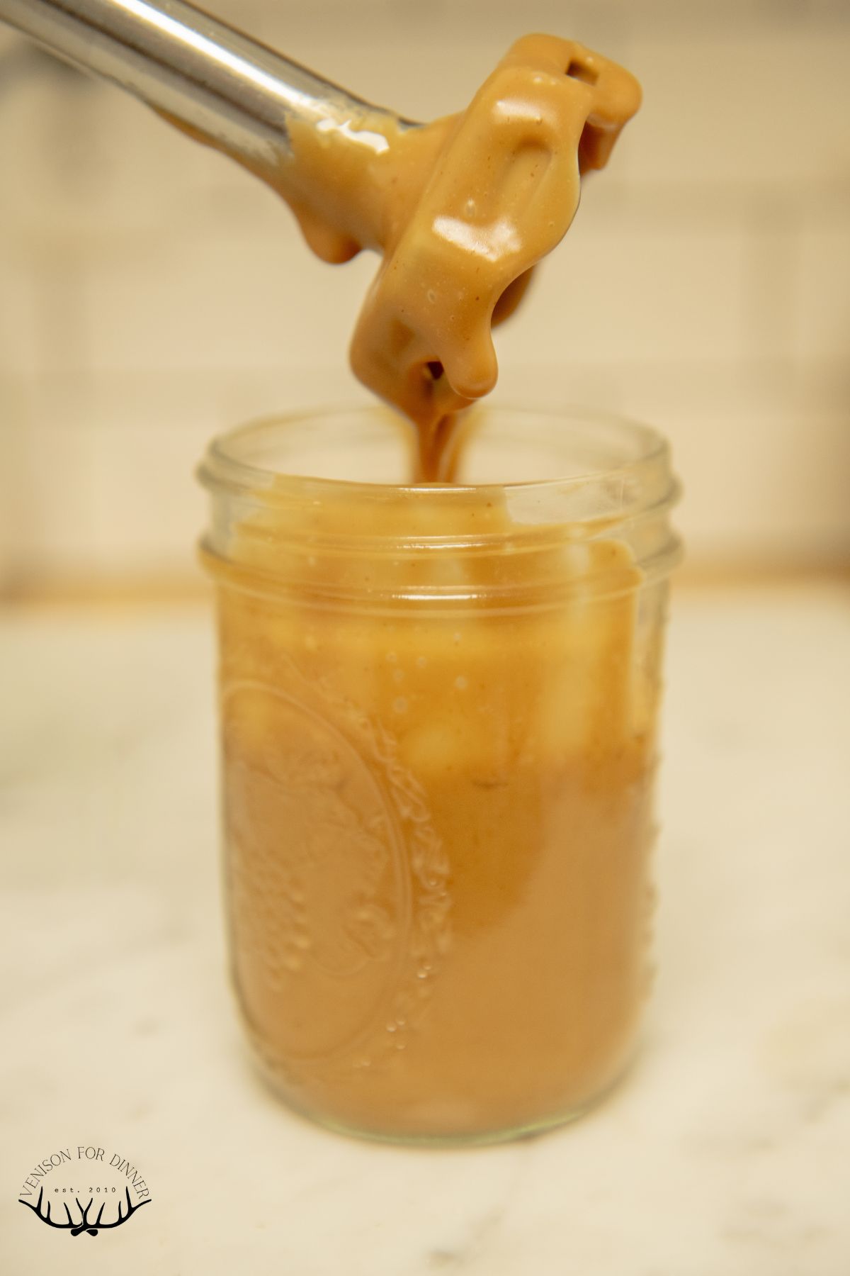 Immersion blender in jar of balsamic dressing.