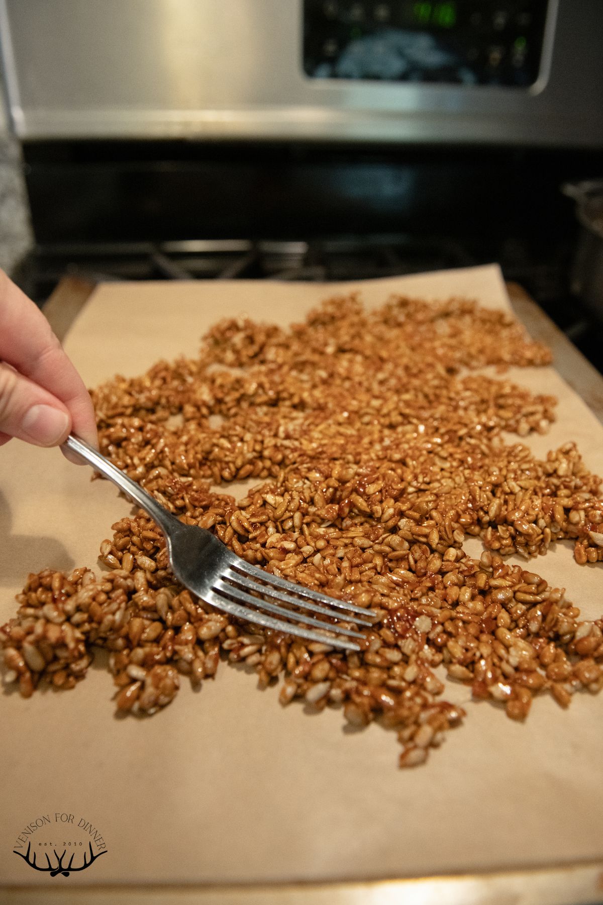 Fork spreading out candied sunflower seeds.