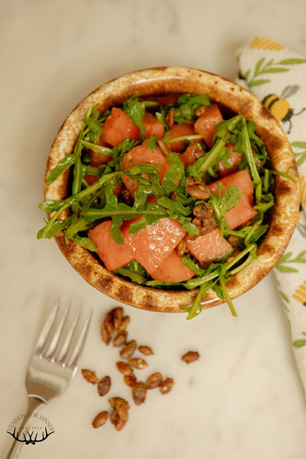 Wooden bowl of arugula watermelon salad.