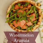 Wooden salad bowl of watermelon and arugula.