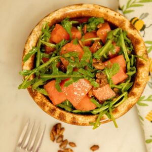 Fork with a bowl of watermelon arugula salad.