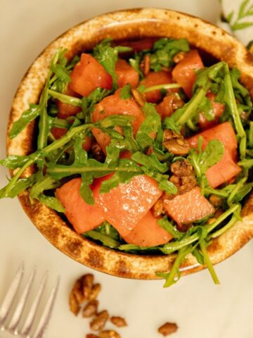 Fork with a bowl of watermelon arugula salad.