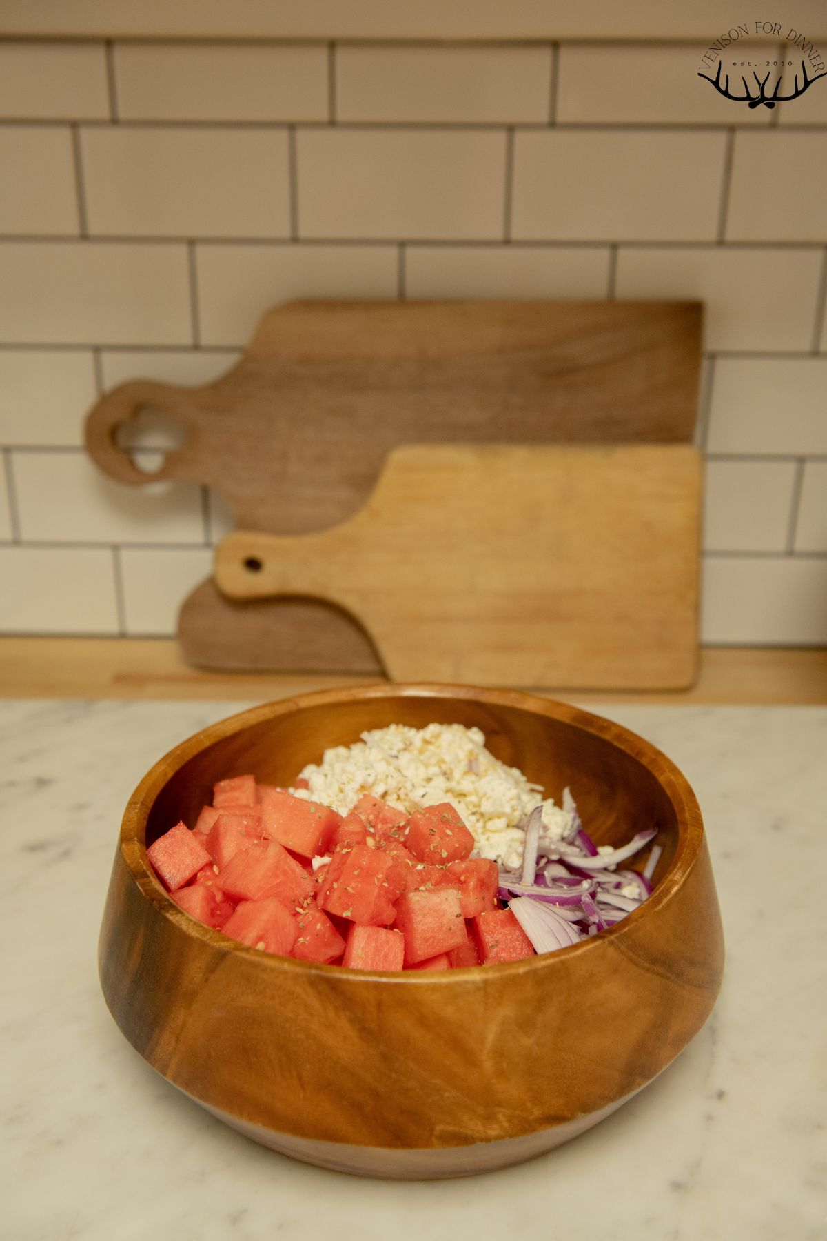 Diced watermelon and feta in a wooden bowl.
