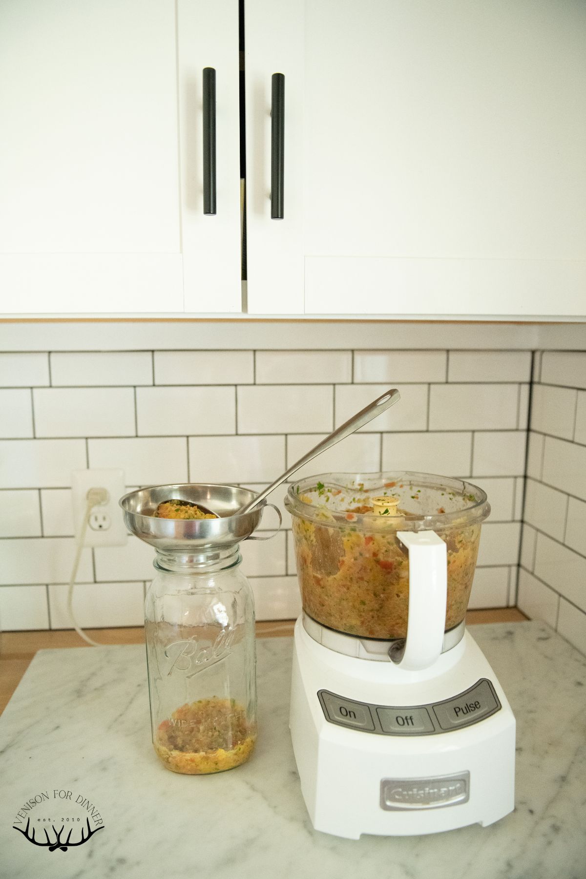 Ladling chopped salsa into a mason jar.